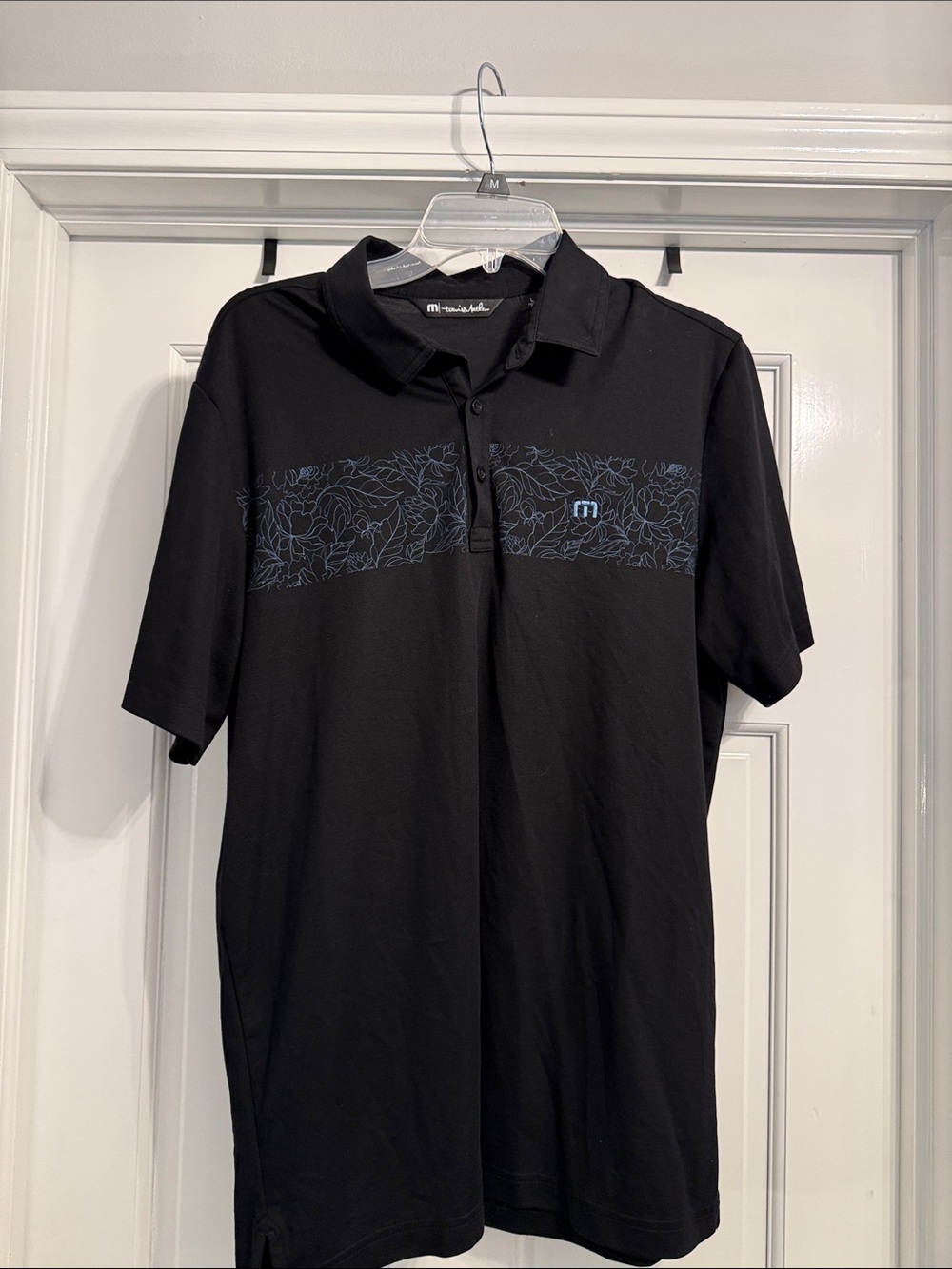 Travis Mathew Black Polo with Blue Floral Chest Stripe